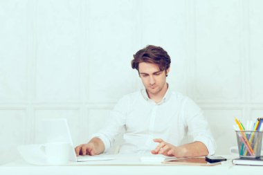 Laptop ve kalem kullanarak tablo oturan işadamı