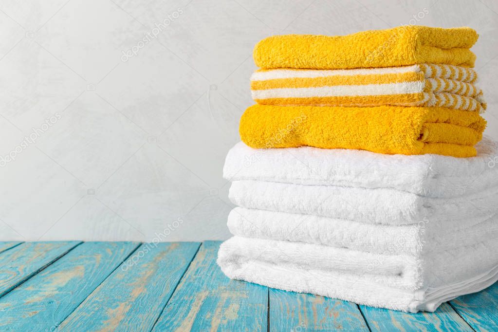 Stack of bath towels on wooden table with copy space