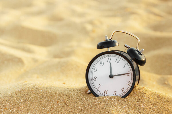 Vacation time. Alarm clock on the sand.
