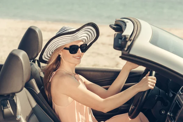 Young woman drive a car on the beach