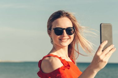 Sahilde cep telefonu ile genç güzel sarışın kadın