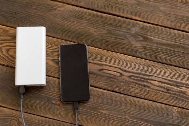 powerbank ve ahşap masa üzerinde cep telefonu