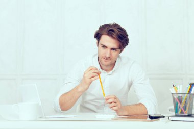 Laptop ve kalem kullanarak tablo oturan işadamı