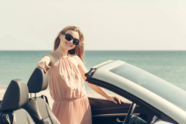 Young woman drive a car on the beach