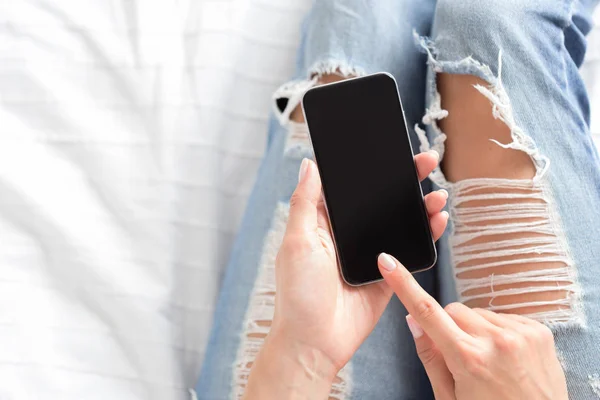 Woman checking the cellphone on the bed