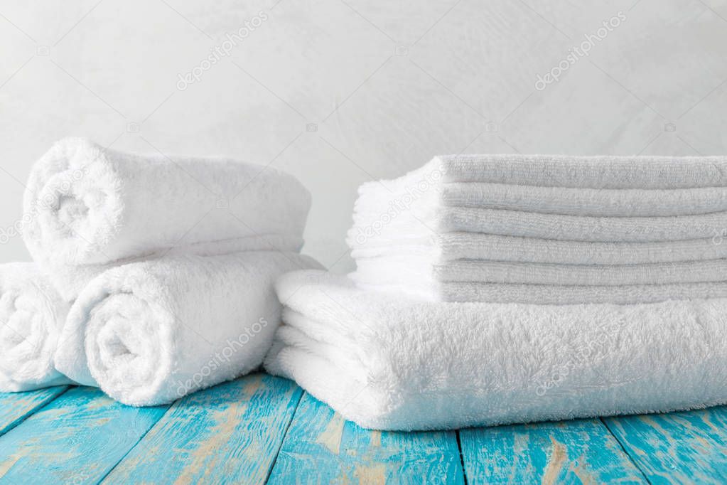Stack of bath towels on wooden table with copy space