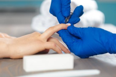 Kadın elleri güzellik salonunda manikür yaptırıyor.