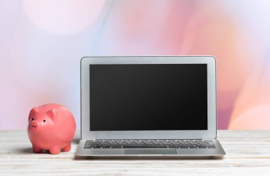 kumbara ve ahşap masa üstünde laptop