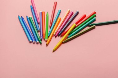 Renkli keçeli kalemlerin pastel pembe arka planda çeşitliliği