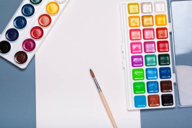 Kağıt, suluboya, boya fırçası ve bazı sanat eserleri üst manzarayı kapatır.