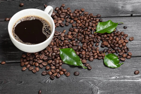 Taza de café y frijoles sobre fondo de madera — Foto de Stock