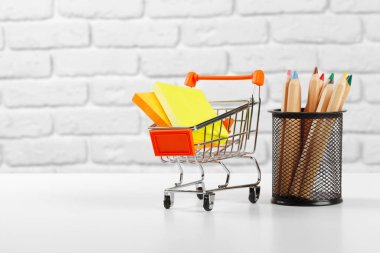 Çok renkli kalemleri ve kalemleri olan mini bir alışveriş arabası. yaratıcı fotoğraf.