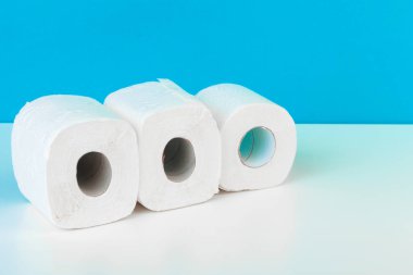 Mavi arka planlı beyaz masada izole edilmiş üç tuvalet kağıdı. yaratıcı fotoğraf.