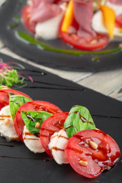 Čerstvý italský caprese salát s mozzarellou a rajčaty na tmavém talíři — Stock fotografie