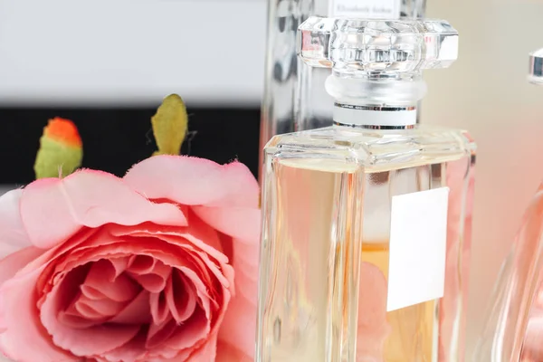 Garrafas de perfume com flores no fundo claro — Fotografia de Stock