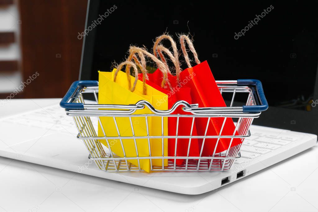 Online shopping concept. Shopping cart, laptop on the desk. creative photo.
