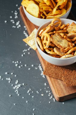 Taş masada bira atıştırmalıkları. Çeşitli krakerler, patates cipsi. Üst görünüm