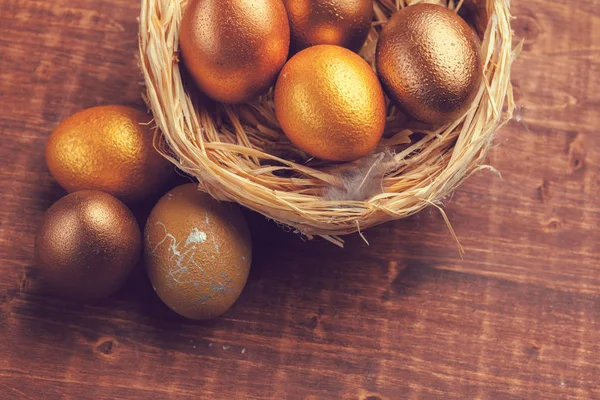 Χρυσά πασχαλινά αυγά σε ξύλινο φόντο. Δημιουργική φωτογραφία. — Φωτογραφία Αρχείου