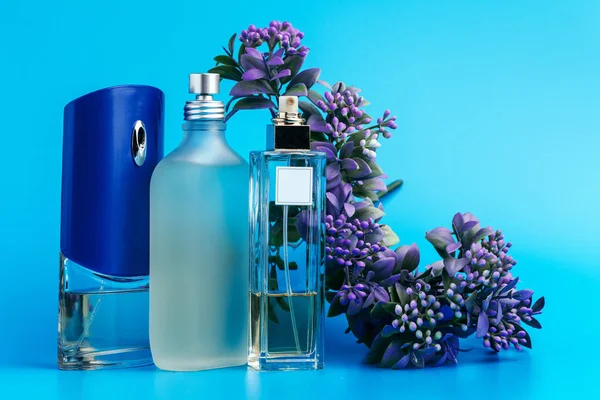 Perfume bottles with flowers on a light blue background — Stock Photo, Image