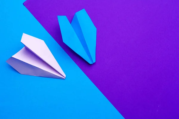 Avión de papel blanco sobre un fondo de papel azul y púrpura — Foto de Stock