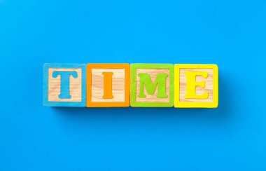 Zaman doldu. Mavi arka planda ahşap renkli alfabe blokları, düz yatış, üst manzara. yaratıcı fotoğraf.