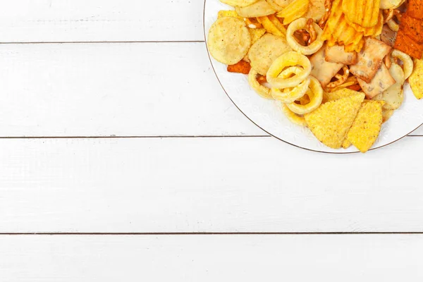 Mieszanka przekąsek: precle, krakersy, frytki i nachos na stole — Zdjęcie stockowe