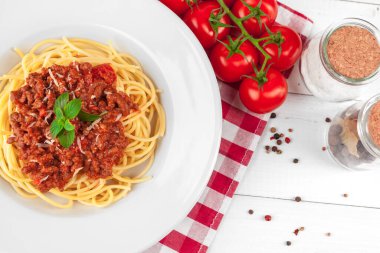 Etli makarna, domates sosu ve sebzeler masada.
