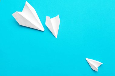 Mavi arka planda beyaz kağıt uçak