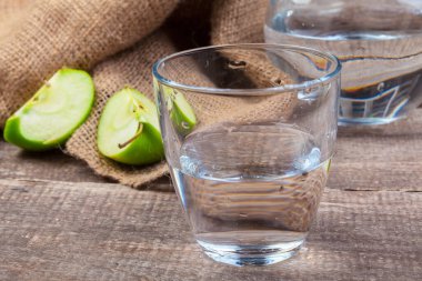 Temiz suda elma dilimleri ve ahşap bir masada taze bir elma ile beslenme içeceği.