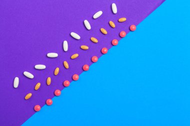 Mavi arka planda bir sürü renkli hap. Üst görünüm.