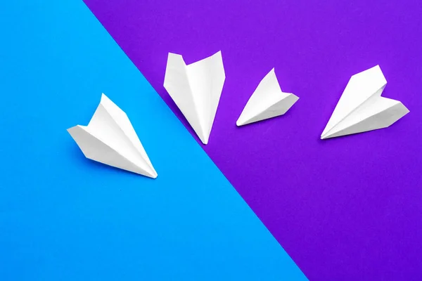 Самолет из белой бумаги на голубом и фиолетовом фоне — стоковое фото