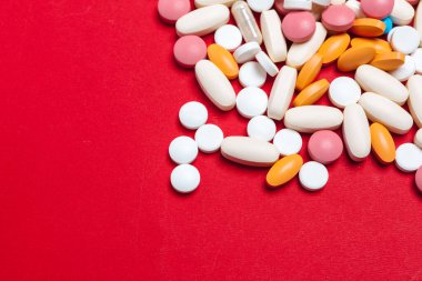 Kırmızı arka planda çok renkli haplar. Tıbbi konsept. Doku.