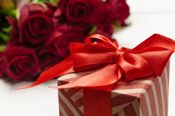 Ένα μπουκέτο κόκκινα τριαντάφυλλα, δώρο και καρδιές στο τραπέζι. Έννοια Ημέρα της Γυναίκας ή Αγίου Βαλεντίνου. Αντιγραφή χώρου — Φωτογραφία Αρχείου