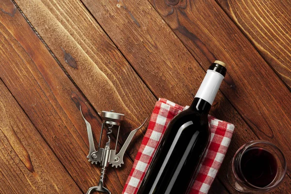 Kırmızı şarap şişesi, şarap kadehi ve ahşap masa arkasında tirbuşon. — Stok fotoğraf