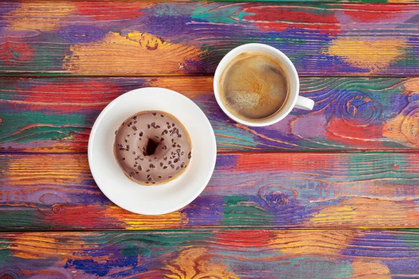 Свежий пончик с кофе на деревянной поверхности, вид сверху — стоковое фото