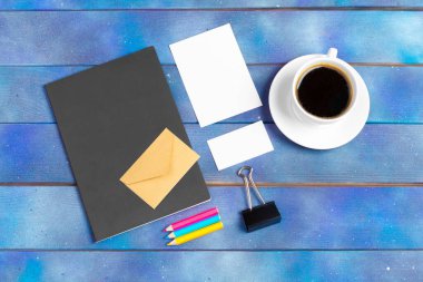 Kontrol listesi için model, mavi ahşap arka planda kahve fincanı olan boş not kağıdı. Ofis, yazar veya öğrenim kavramı