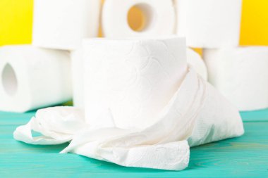 Sarı kağıdın üzerine istiflenmiş tuvalet kağıdı ruloları.