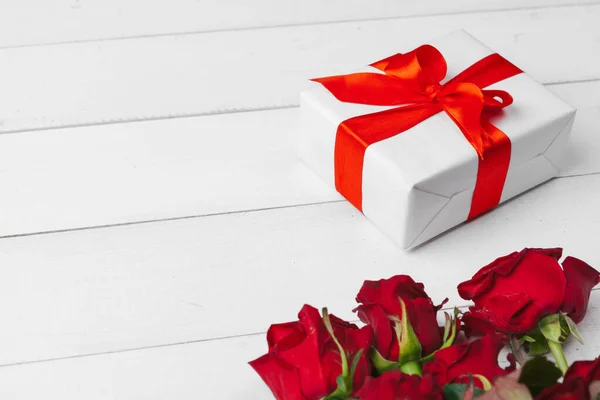 Sv. Valentýna. Červené růže a dárková krabička na dřevěném stole — Stock fotografie