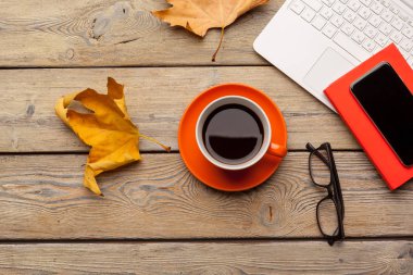 Tahta masadaki turuncu tabakta bir fincan kahve. Ofis içi