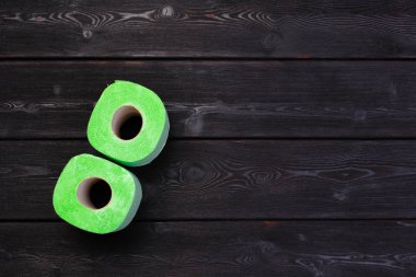 Siyah ahşap arka planda yeşil tuvalet kağıdı yuvarlanıyor.