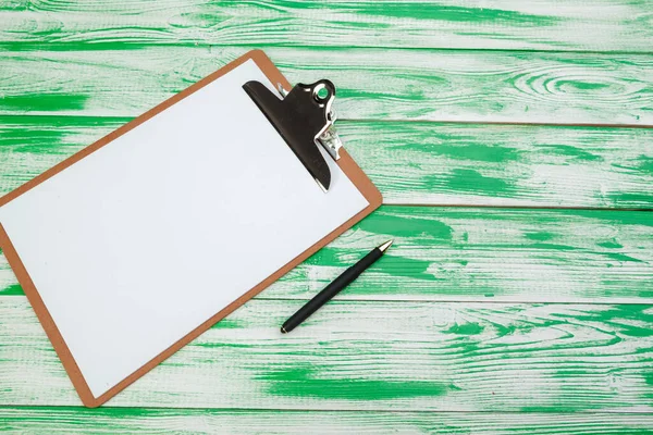 Clipboard with office supplies on green wooden table, flat lay