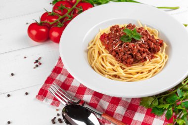 Etli makarna, domates sosu ve sebzeler masada.