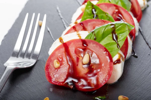 Čerstvý italský caprese salát s mozzarellou a rajčaty na tmavém talíři — Stock fotografie