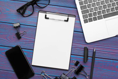 Boş not defteri, dizüstü bilgisayarı ve ofis malzemeleri olan ofis masası.