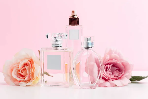 Пляшка парфумів з квітами на кольоровому фоні — стокове фото
