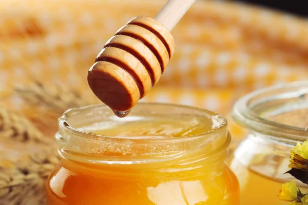 Honung bakgrund. Söt honung i glasburk på trä bakgrund. — Stockfoto