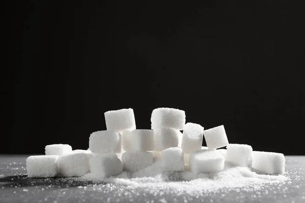 Sugar lumps piled up together against a black background