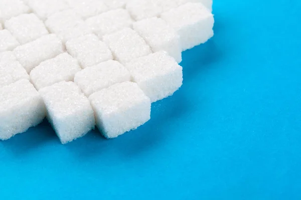 Cubes de sucre blanc sur un fond bleu vif — Photo
