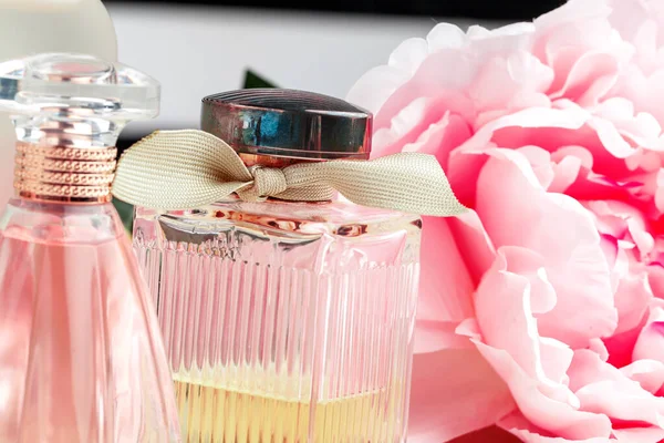 Bouteilles de parfum avec des fleurs sur fond clair — Photo