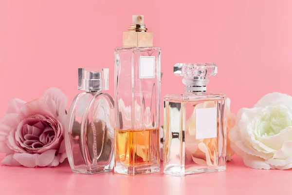 Духи бутылка с розами на розовом фоне ткани — стоковое фото